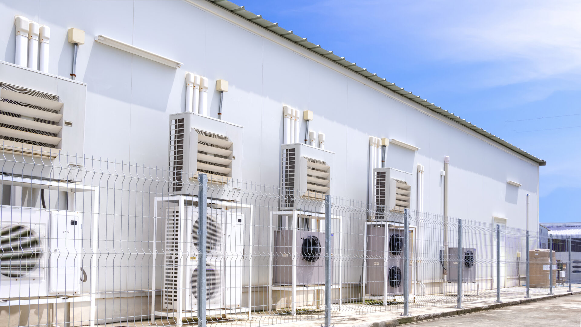 Group of air conditioner compressors with ventilation equipment in HVAC System with pipelines on backside wall of convenience store against blue sky Grocery Store Design and Construction